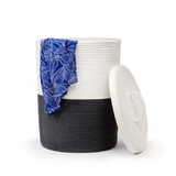 A cotton rope, white and grey House of York Deluxe Laundry basket, with a blue cloth partially covering the top speaker, set against a white background. The lid of the laundry basket is placed beside it.
